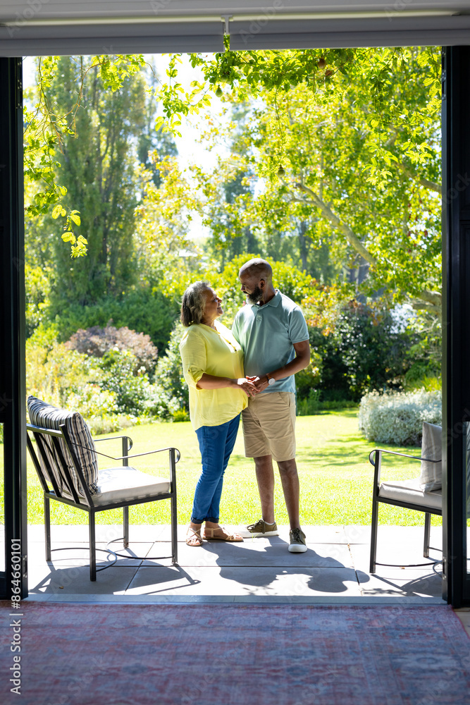 Couple standing on patio, holding hands and smiling at each other Couple standing on patio, holding hands and smiling at each other