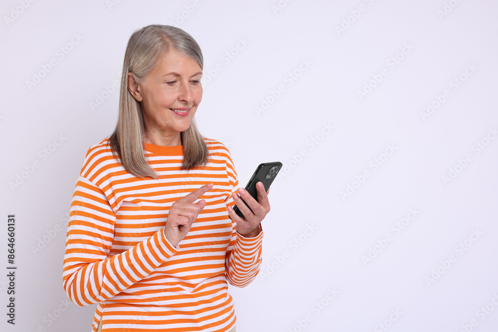 Senior woman with phone on light grey background, space for text