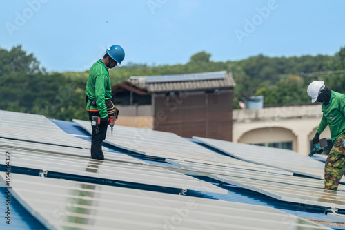 Worker Technicians are working to construct solar panels system on roof. Installing solar photovoltaic panel system. Men technicians walking on roof structure to check photovoltaic solar modules.