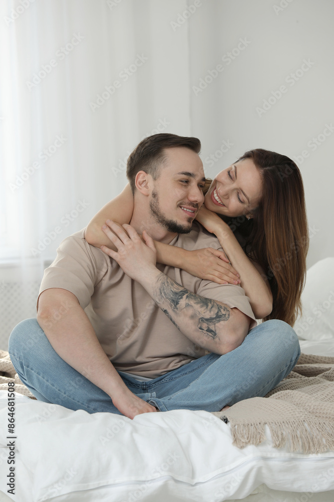 Happy couple sitting on bed and hugging at home Happy couple sitting on bed and hugging at home