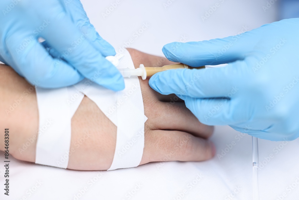 Nurse inserting IV into arm of patient in hospital, closeup Nurse inserting IV into arm of patient in hospital, closeup