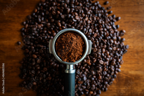 .Top view, ground in portafilter on coffee beans and wood background..