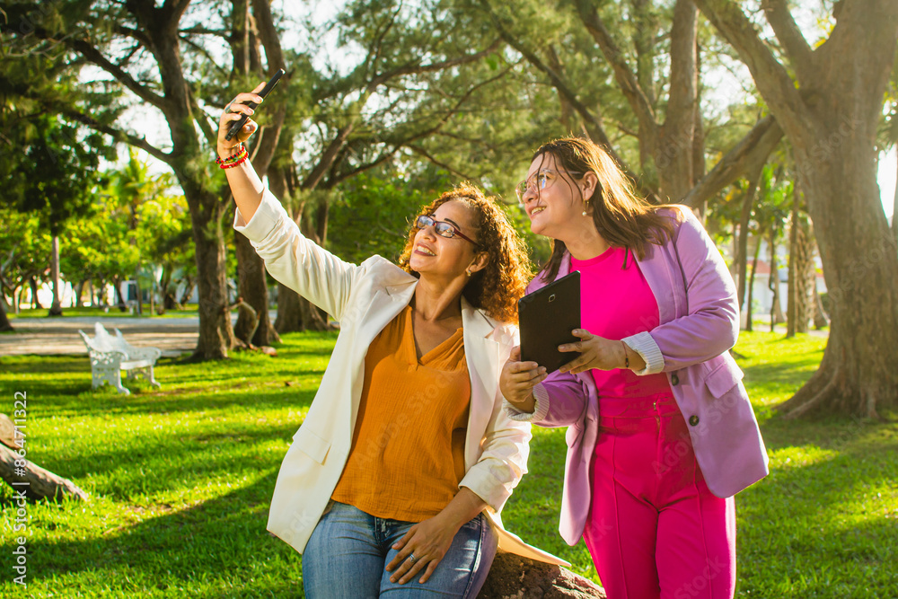 Fototapeta premium Friends sharing a digital moment in the park