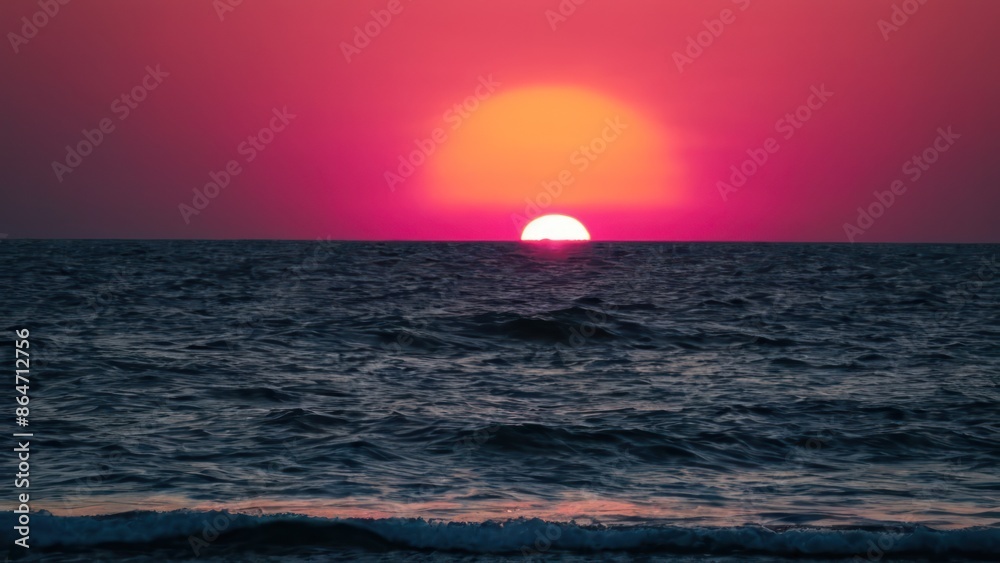 a photograph of the sun is setting over the ocean and the water is blue and pink in color a photograph of the sun is setting over the ocean and the water is blue and pink in color