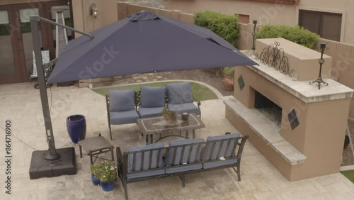 An aerial 4k video of a Deseret landscaped backyard in Arizona featuring a travertine tiled pool deck with a spa, outdoor fireplace, outdoor kitchen and putting green.