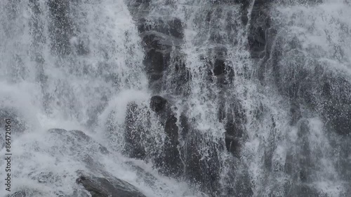 Close up.Waterfalls cascade down quickly through black rocks.