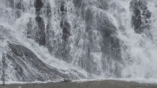 Close-up of a waterfall flowing violently on a black rock cliff.