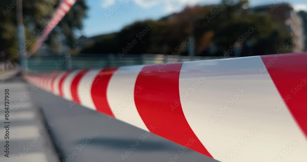 A red and white ribon striped barrier is on the road at traffic accident