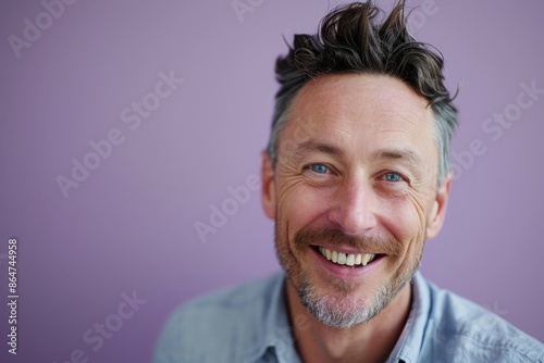 Portrait of a handsome mature man smiling against a purple background.