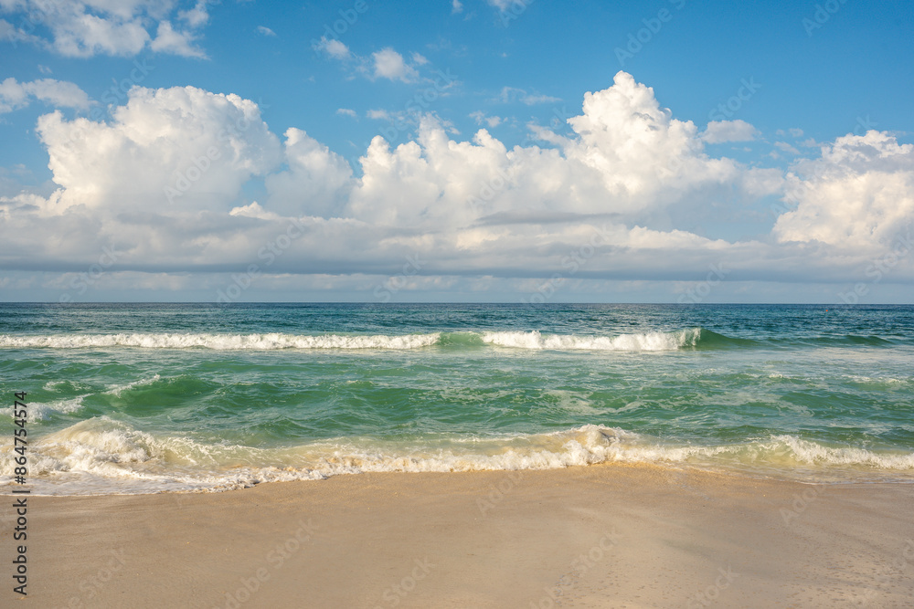 Photo of ocean waves crashing on a beautiful sandy beach with beautiful clouds in the blue sky. Photo of ocean waves crashing on a beautiful sandy beach with beautiful clouds in the blue sky.