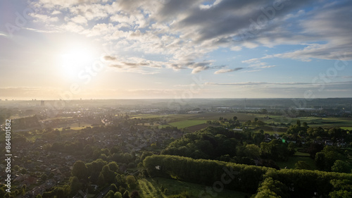 The morning view is vibrant with green fields, houses, and a stunning sunrise, exuding tranquility and beauty