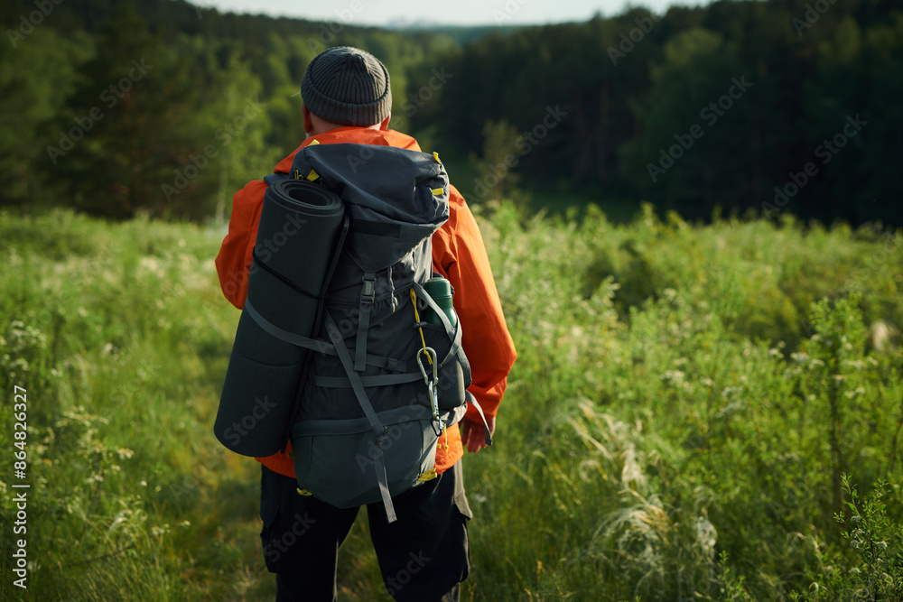 Medium long back view shot of unrecognizable male tourist wearing backpack hiking on summer day, copy space Medium long back view shot of unrecognizable male tourist wearing backpack hiking on summer day, copy space