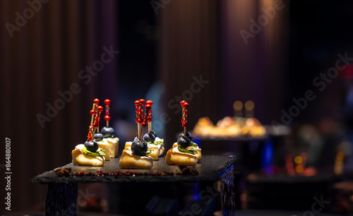 Foto Close-up shot of small, savory appetizers adorned with blueberries arranged on a black slate platter at a catered event