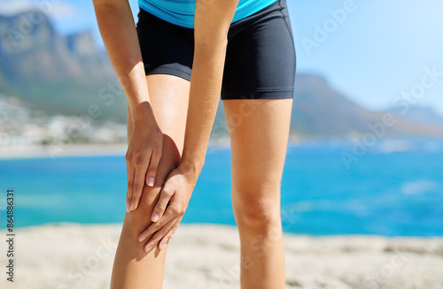 Exercise, knee pain and woman by beach with injury, muscle strain and accident from training. Sports, health and athlete with inflammation, tension and medical risk from fitness, workout and wellness