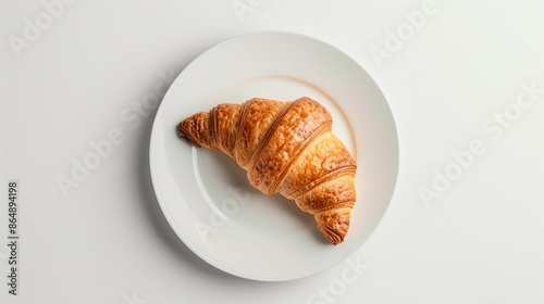 A minimalist shot featuring a single, perfectly baked croissant on a white plate, set on a clean surface with ample copy space