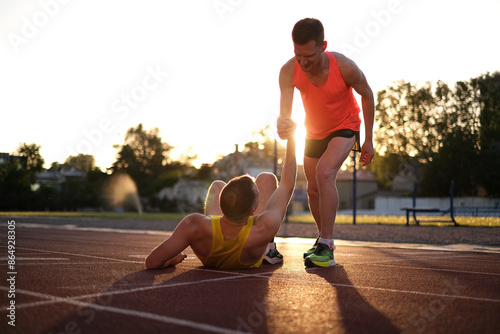 Photography One athlete helps another to stand up after being injured while running at the s