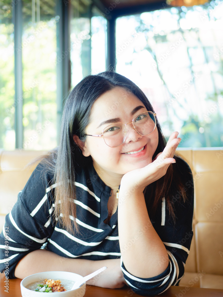 A cheerful, plump Asian woman savors her meal at a restaurant. A cheerful, plump Asian woman savors her meal at a restaurant.