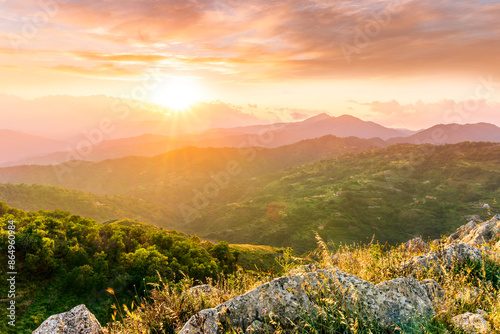 Fototapeta Naklejka Na Ścianę i Meble -  highland mountain landscape of beautiful sunset or sunrise with nice mountain peaks and slopes, green and golden hills and majestic cloudy sky on background