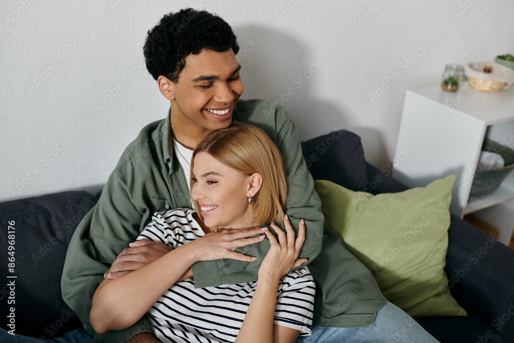 A young couple, embracing on a sofa in a modern apartment, share a moment of intimacy and laughter. A young couple, embracing on a sofa in a modern apartment, share a moment of intimacy and laughter.