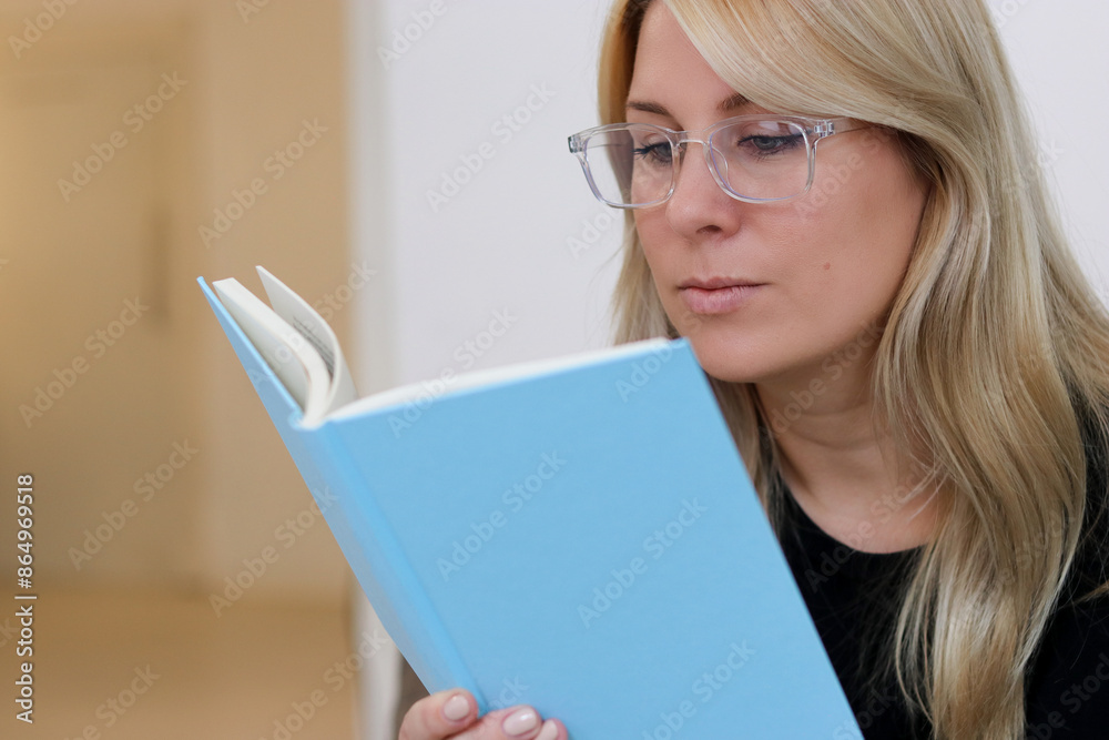 Close up portrait of a caucasian millennial female with glasses siting on a couch and reading a book Close up portrait of a caucasian millennial female with glasses siting on a couch and reading a book