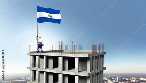 A construction worker proudly raises the El Salvador flag atop a new building, symbolizing progress and the construction of new real estate