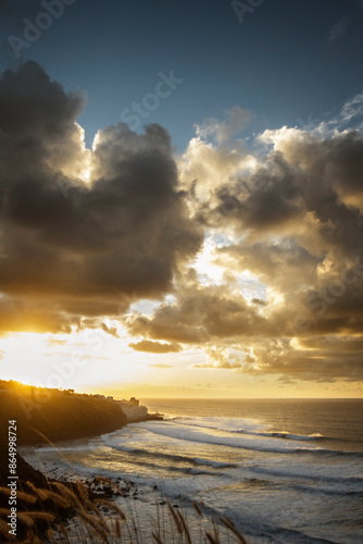 Sunset on the coast, golden clouds at sunset over the sea agitated by the waves and fishing village in the background. Big clouds in the sky. Paradise. Sky. Tenerife, canary islands spain