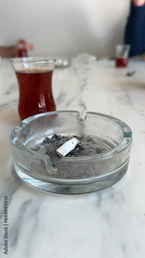 People smoking and drinking tea at a table. Only hands are visible People smoking and drinking tea at a table. Only hands are visible