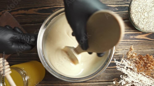 Person mixes the soap mass in the process of making soap. The master mixes the ingredients in the workshop.