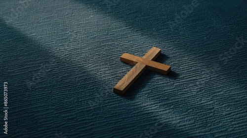 A simple wooden cross lies on a sunlit wooden floor.