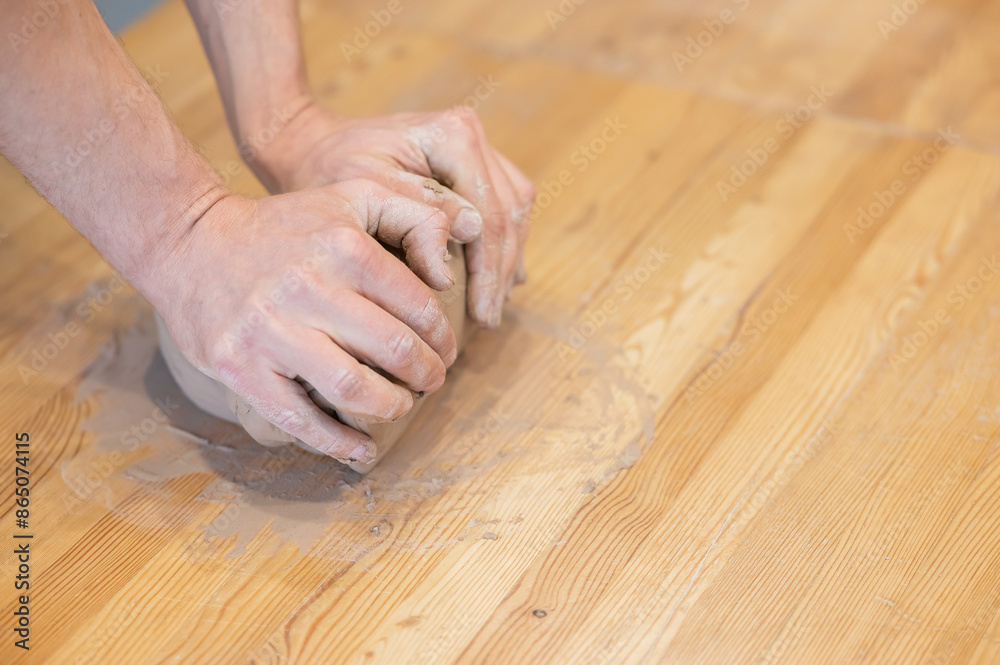 A potter kneads clay before using it in the workshop. Close-up of a man's hands. A potter kneads clay before using it in the workshop. Close-up of a man's hands.