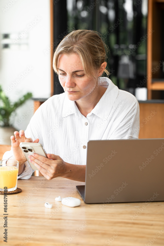 A woman works at a computer and talking on smartphone. Home office. Information Technology. Search for information on the Internet. Freelancing. A woman works at a computer and talking on smartphone. Home office. Information Technology. Search for information on the Internet. Freelancing.