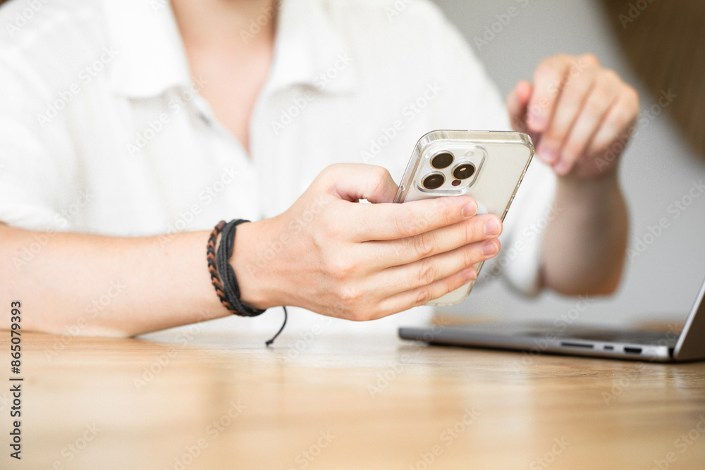 Fototapeta premium Freelancing. A man surfs the Internet, searching for information on the Internet. A man touches the phone screen with his finger. Scroll the web. Communication via smartphone. 