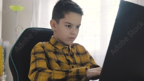 Smart young boy works on a laptop for his new project at home.