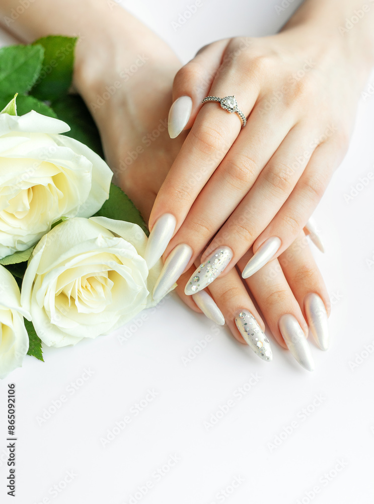 Female Hands on a white background with beautiful pearl manicure and white roses. Female Hands on a white background with beautiful pearl manicure and white roses.
