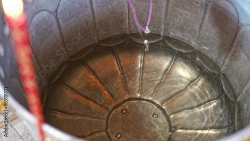 The priest's hand holds the cross on a chain and dips it into the holy water in the baptismal font. The Sacrament of Baptism in the Orthodox Church.