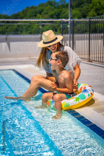 Mother and kid playing sitting on a swimming pool photo