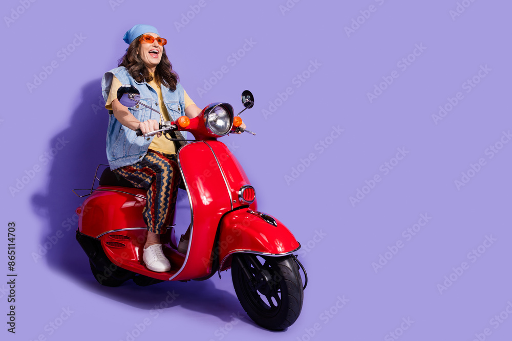 Full length photo of pensioner lady ride motorcycle excited dressed stylish denim hipster garment isolated on purple color background Full length photo of pensioner lady ride motorcycle excited dressed stylish denim hipster garment isolated on purple color background