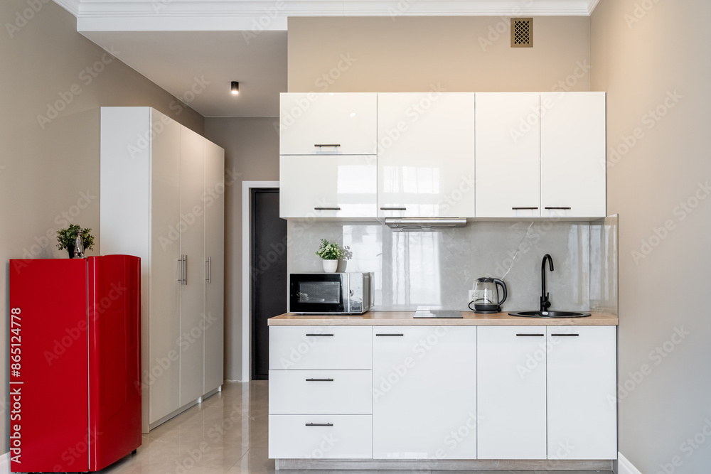 Fototapeta premium stylish interior of apartment with modern kitchen in white. kitchen design with appliances, microwave, red refrigerator, stove. 