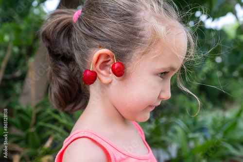 Bild auf Leinwand A cherry in the ear of a smiling girl.