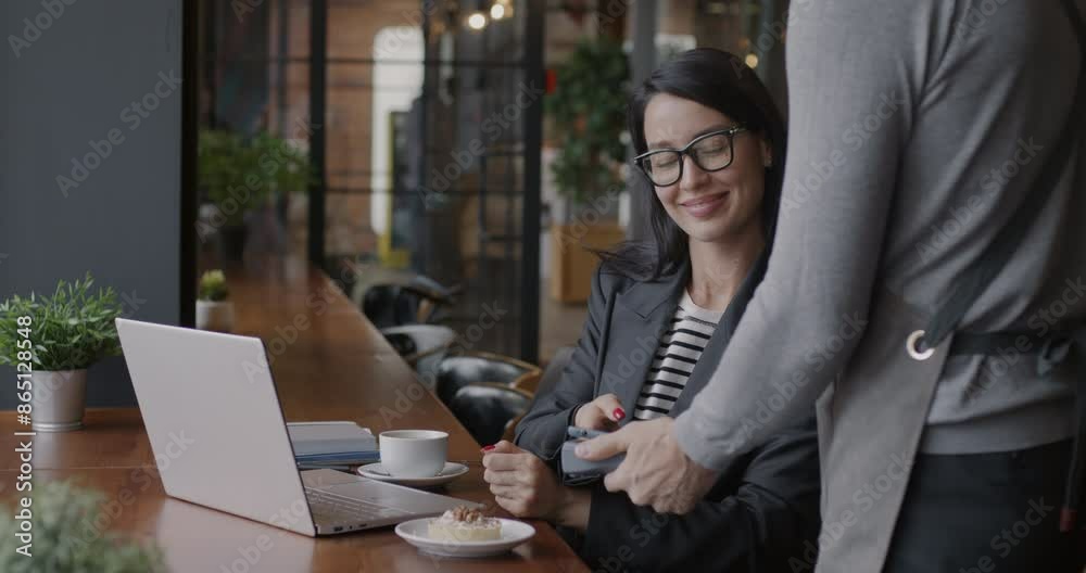 Successful businesswoman paying for order in cafe using smartphone and NFC payment machine talking to waiter. Modern technology and businessperson concept.