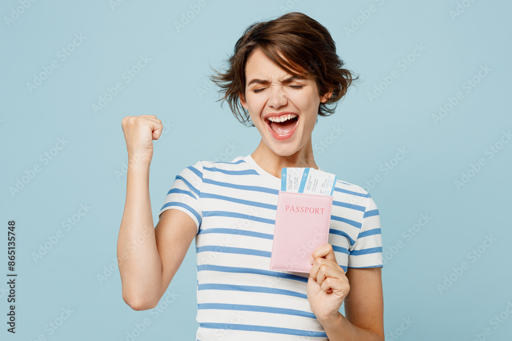 Traveler winner woman wear striped casual clothes hold passport ticket isolated on plain pastel blue background. Tourist travel abroad in free spare time rest getaway. Air flight trip journey concept. Traveler winner woman wear striped casual clothes hold passport ticket isolated on plain pastel blue background. Tourist travel abroad in free spare time rest getaway. Air flight trip journey concept.