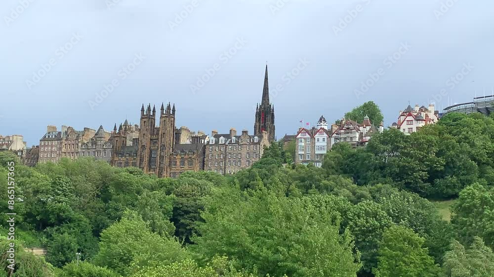 University of Edinburgh in the historic, gothic old town. A church spire is visible behind and lush green foliage moving and birds flying in the wind in the foreground. University of Edinburgh in the historic, gothic old town. A church spire is visible behind and lush green foliage moving and birds flying in the wind in the foreground.
