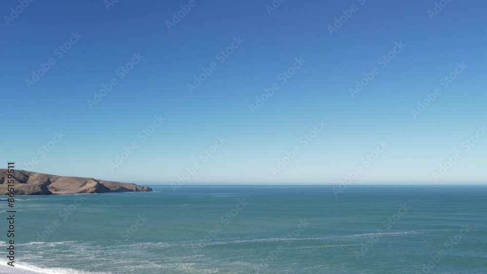 High altitude slow reverse above beautiful turquoise ocean with sloping land, incoming waves and stony beach -Birdlings Flat Beach, New Zealand High altitude slow reverse above beautiful turquoise ocean with sloping land, incoming waves and stony beach -Birdlings Flat Beach, New Zealand
