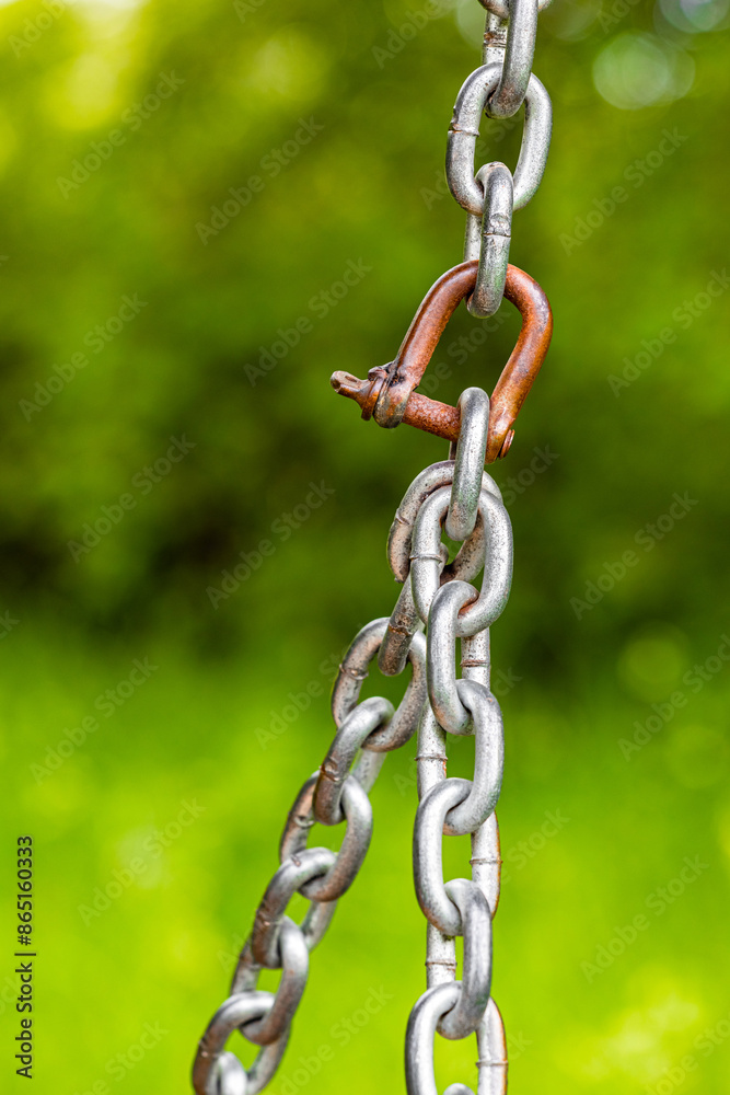 metal chain on a background of green foliage. fragment of an old metal chain. metal chain mount. reliable metal fastening. vertical photo metal chain on a background of green foliage. fragment of an old metal chain. metal chain mount. reliable metal fastening. vertical photo