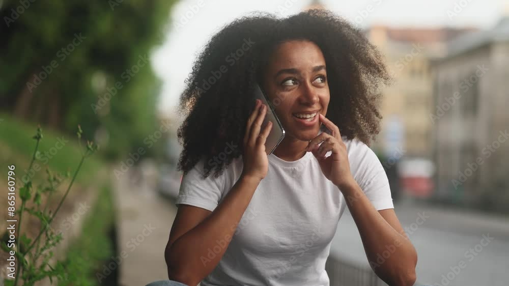 Portrait of young dark haired pretty woman having phone call working or personal conversation on smartphone at city street Happy smiling curly female talking by mobile phone outdoors Portrait of young dark haired pretty woman having phone call working or personal conversation on smartphone at city street Happy smiling curly female talking by mobile phone outdoors