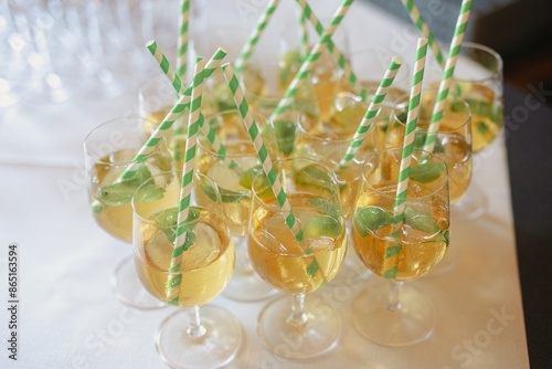 Elegant wedding cocktails with striped paper straws, served in glassware with fresh basil leaves, perfect for a summer celebration.
