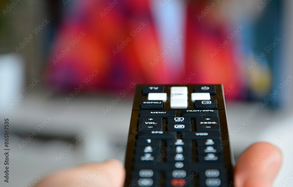 dłoń trzymajaca pilota TV, przełączanie programów telewizyjnych za pomoca pilota, relax watching TV and using remote control, hand with remote control changes channels, hand holds TV remote control.