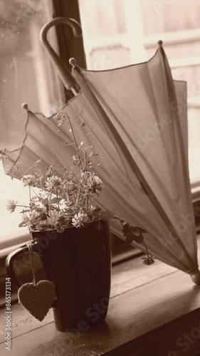 Vertical video. Summer flowers in the cup on the window sill, umbrella, rainy seoson.  atmospheric mood. Vintage sepia effect.  photo