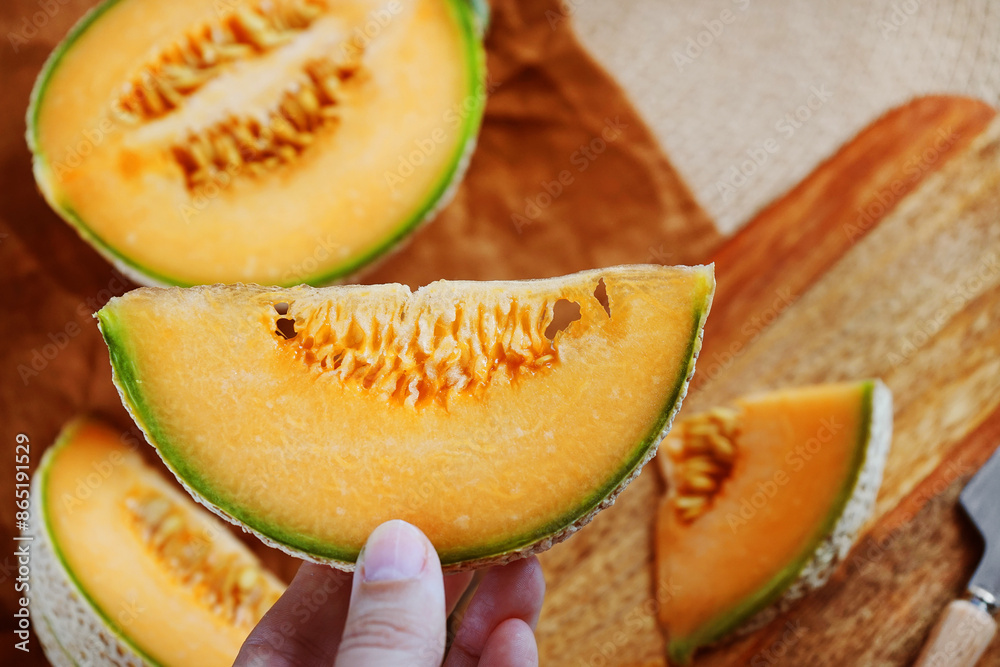 Ripe yellow melon cut into slices on a wooden board next to a knife and linen napkin Ripe yellow melon cut into slices on a wooden board next to a knife and linen napkin