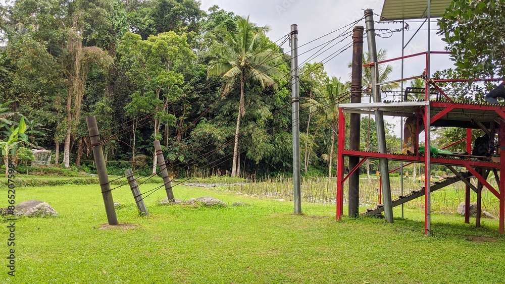 Old wooden swing in the park with green grass and trees background. Old wooden swing in the park with green grass and trees background.